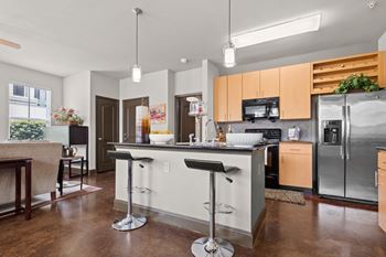 A kitchen with stainless steel appliances and an island with bar stools